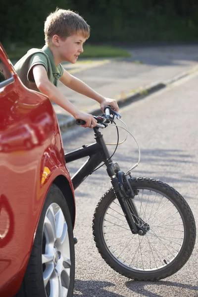 Criança equitação bicicleta por trás estacionado carro — Fotografia de Stock
