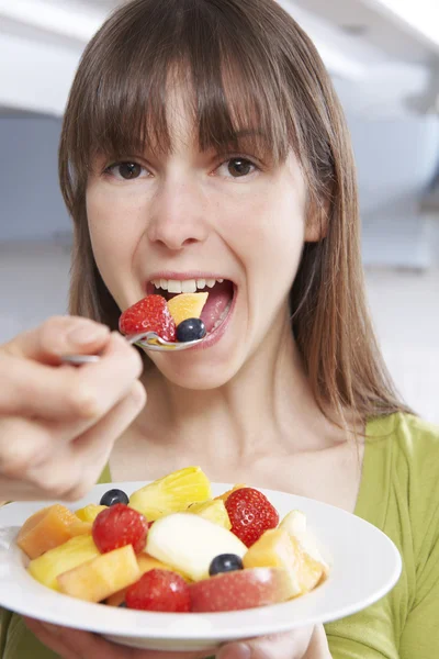 Ung kvinna äta skål med färsk fruktsallad — Stockfoto