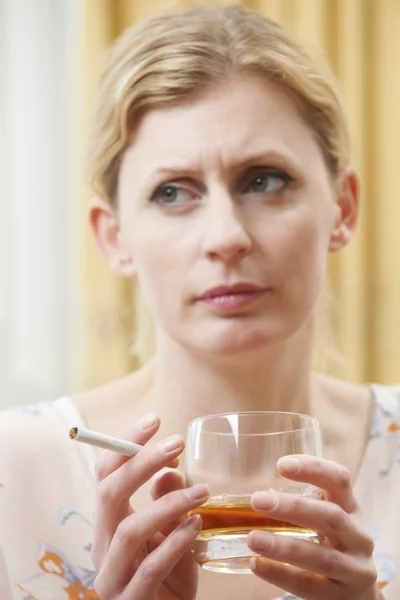 Mulher segurando vidro de uísque e cigarro — Fotografia de Stock