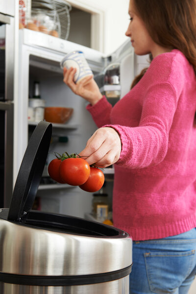 Woman Throwing Away Out Of Date Food In Refrigerator
