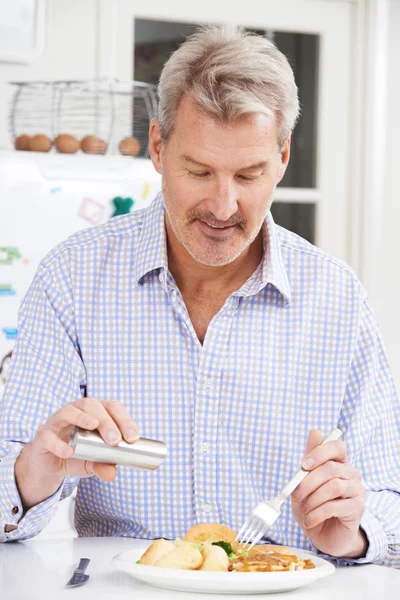 Man At Home Adding Salt To Meal — Stock Photo, Image