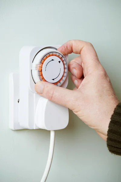 Hombre ajustando temporizador en enchufe eléctrico —  Fotos de Stock