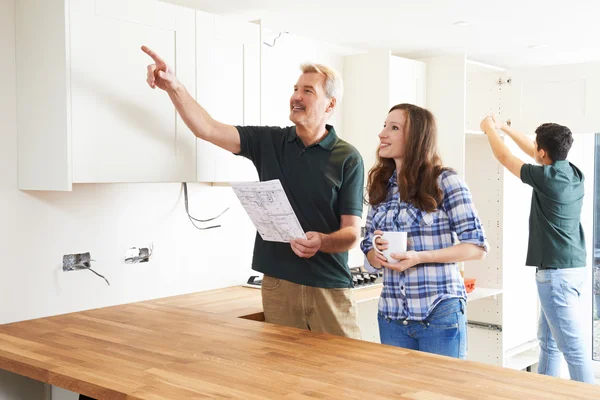 Woman With Carpenter Looking At Plans For New Kitchen — Stock Photo, Image