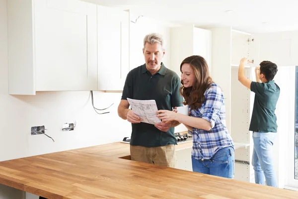 Vrouw met Carpenter kijken naar plannen voor nieuwe keuken — Stockfoto