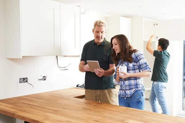 Woman With Carpenter Looking At Plans For Kitchen On Digital Tab — Stock Photo, Image