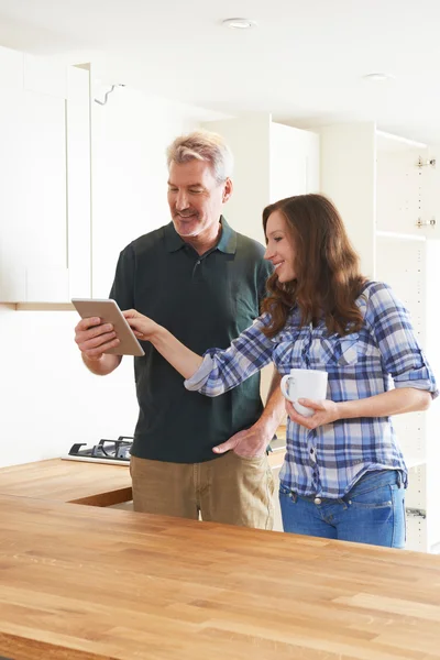 Kvinna med snickare titta på planer för kök på Digital fliken — Stockfoto