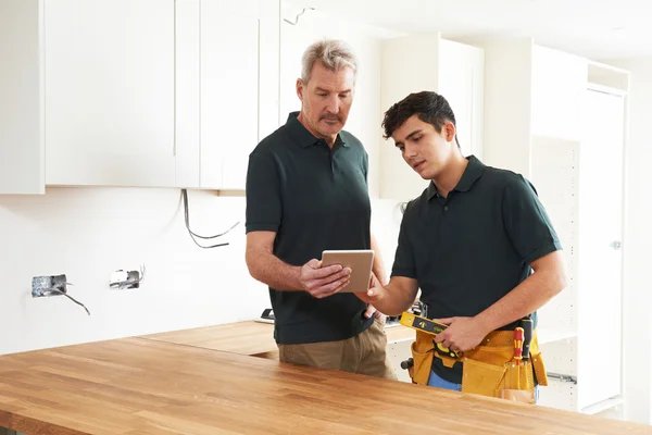 Carpenter And Apprentice With Digital Tablet Fitting Luxury Kitc — Stock Photo, Image