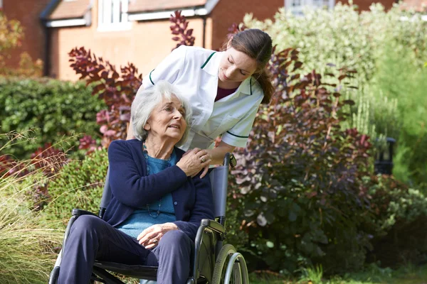 CARER trycka senior kvinna i rullstol — Stockfoto