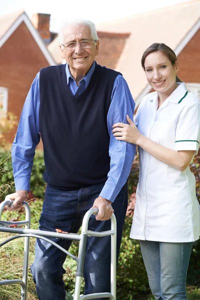 Pflegerin hilft Seniorin mit Rollator im Garten — Stockfoto