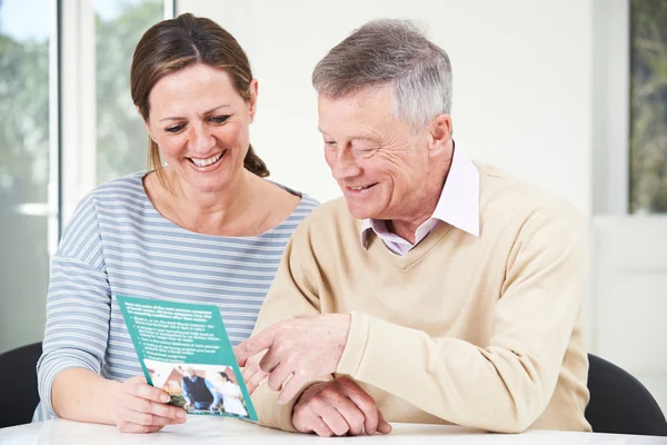 Senior mit erwachsener Tochter schaut sich Broschüre für Rentner an — Stockfoto