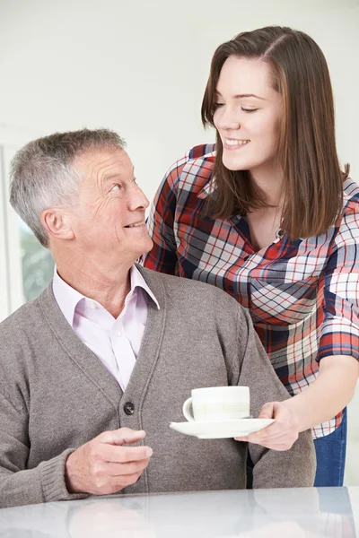 Подростковая внучка приносит дедушке горячий напиток — стоковое фото
