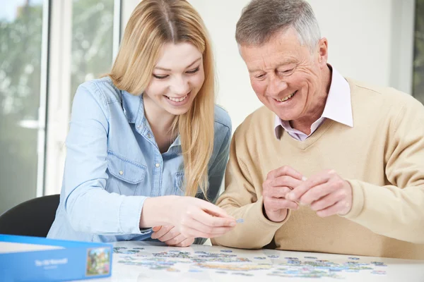 Tiener kleindochter helpende grootvader met Jigsaw puzzel — Stockfoto