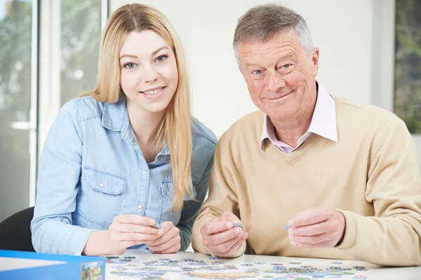 Adolescente petite-fille aider grand-père avec puzzle — Photo