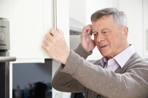 食器棚で探している物忘れの年配の男性 — ストック写真