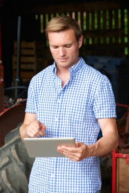 Dijital Tablet eski Fashione ile ahırda ayakta tutan çiftçi