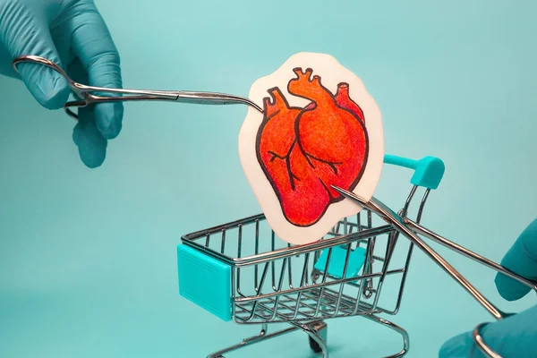 doctors hand lowers heart into shopping cart.