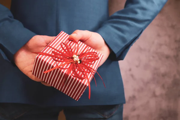 close up of man hands holding gift box behind his back