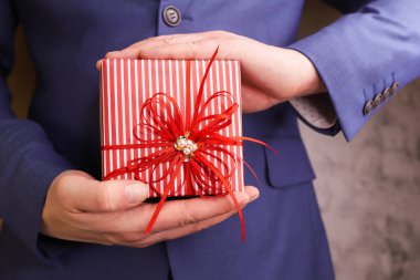 Takım elbiseli adam hediye kutusunu tutuyor..