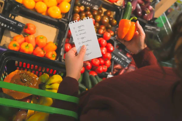 Female customer follows shopping list. buying fruits and vegetables in market. — Stock Photo, Image