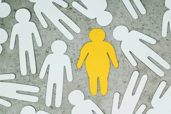 Silueta amarilla del hombre gordo en el centro alrededor de las personas con peso normal. — Foto de Stock