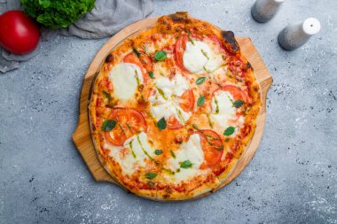 Domatesli İtalyan pizzası, mozzarella ve güzel gri masada fesleğen.