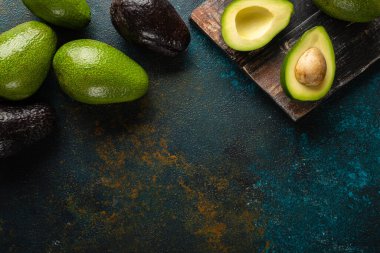Koyu kırsal bir arkaplanda avokado. Koyu tahta üst görünümde. Metnin için kopyalama alanı ile birlikte..