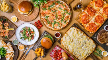 Masada çeşitli yiyecekler var. Roma hamurunda Quattro formaggi pizza, jambonlu pizza, burglar, karides, biftek, patates kızartması..