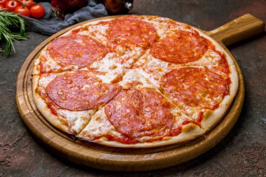 Koyu beton kırsal arka planda panoda sucuklu pizza.