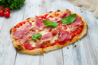 Beyaz ahşap tahtada parmalı jambonlu pizza.