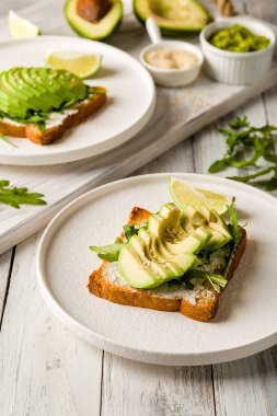 Avokado, krem peynir, guacamole ve roka ile beyaz ahşap masa.