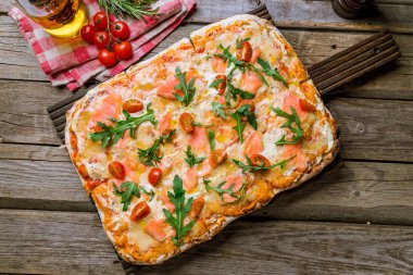 Roma hamurlu, domatesli ve aragüllü somonlu pizza.