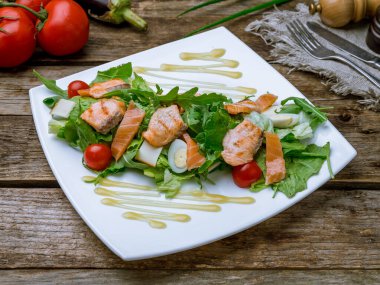 Eski ahşap masada somonla karışık salata.