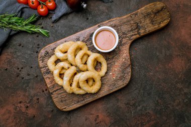 Tahtasında koyu beton kırsal arkaplan soslu kalamar halkaları.