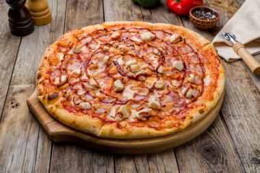 Tavuk eti ve barbekü soslu pizza eski ahşap masada.