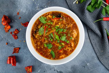 Baharatlı ekşi çorba Çin mutfağı gri masada.