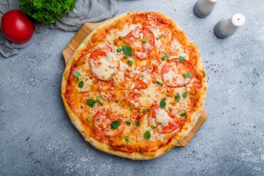 Domatesli İtalyan pizzası ve güzel gri masada fesleğen.
