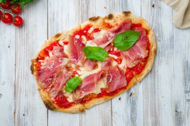 Beyaz ahşap tahtada parmalı jambonlu pizza.