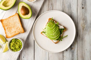 Avokado, krem peynir, guacamole ve roka beyaz ahşap masa manzaralı.