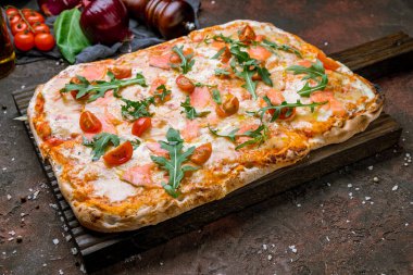 Roma hamurlu, domatesli ve aragüllü somonlu pizza.