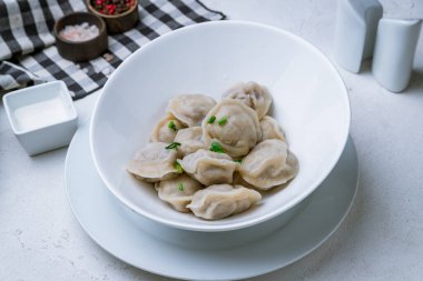 Ekşi kremalı hamur tatlısı ve beyaz beton masada otlar.