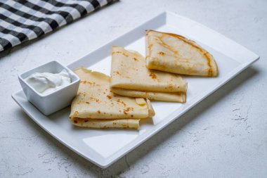 Beyaz tabakta ekşi kremalı krep.