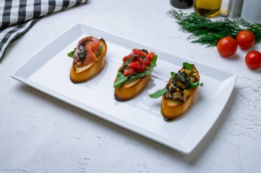 Beyaz tabakta çeşitli bruschett tabakları.