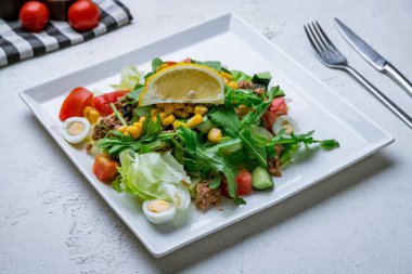 Beyaz tabakta ton balığı ve sebze salatası.