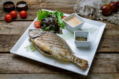 Dorado ızgarada beyaz tabakta eski ahşap masada