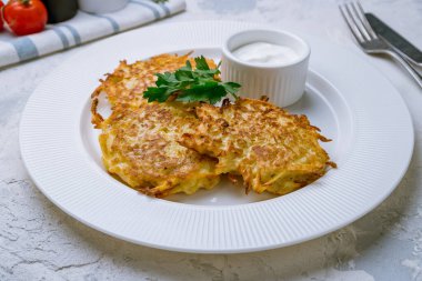 Beyaz tabakta ekşi kremalı kızarmış patates gözlemesi.