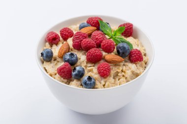 Beyaz zemin üzerinde ahududu, badem ve yaban mersini ve nane ile yulaf ezmesi izole edilmemiş.