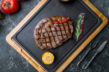 Tahtada pirzola, biftek, mısır, biber ve biberiye.