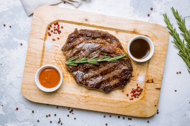 Sulu pirzola, soslu biftek ve ahşap tahtada biberiye.