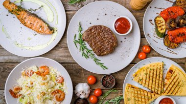 Somon bifteği, sebze salatası, domuz sosisi, deniz ürünleri salatası ve peynirli ızgara pastırma.