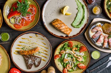 Somon bifteği, sebze salatası, domuz sosisi, deniz ürünleri salatası ve peynirli ızgara pastırma.